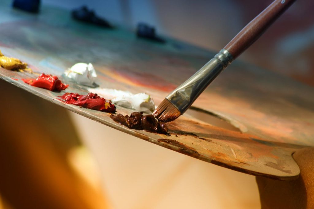 shallow-focus-photography-of-paintbrush-102127 Vibrant artist palette with paint and brush creating colorful artwork.